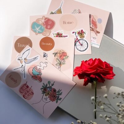 A vibrant flower alongside an assortment of stickers on a tabletop.