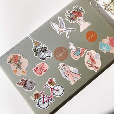 A laptop covered in stickers, accompanied by blooming flowers, representing a fusion of personal expression and natural beauty.