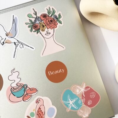 A laptop covered in colorful stickers featuring various designs and patterns.