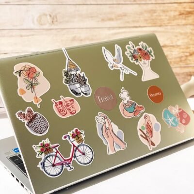A laptop covered in colorful stickers next to a wooden surface.