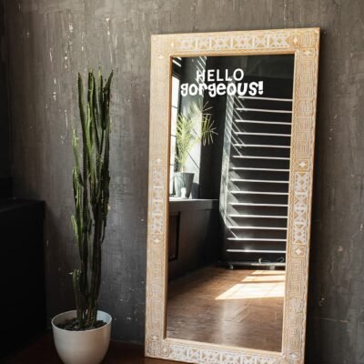 A vibrant mirror with the words 'HELLO gorgeous!' reflecting natural light in a modern, trendy space.