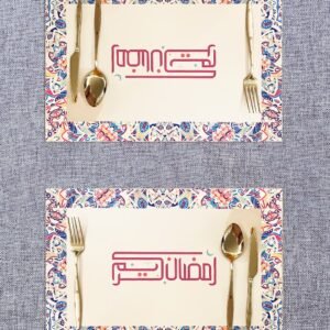 Two ornate place settings on a textured table, each with colorful, patterned borders. Gold cutlery surrounds Arabic text in elegant pink script.
