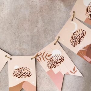 Banner with Arabic calligraphy featuring a Ramadan greeting. Earth-toned designs with minimalistic landscapes and crescent moons. Pink flowers adorn the top.