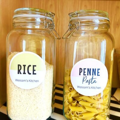 Two glass jars with metal clasps sit on a striped surface. One contains rice labeled 