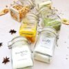 Six labeled glass jars hold chickpeas, turmeric, sugar, salt, fennel, and flour. They're arranged on a white surface with scattered spices.