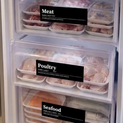 Clear freezer with labeled sections for meat, poultry, and seafood in trays. Frozen vegetables in small bags on top. Neat, organized presentation.