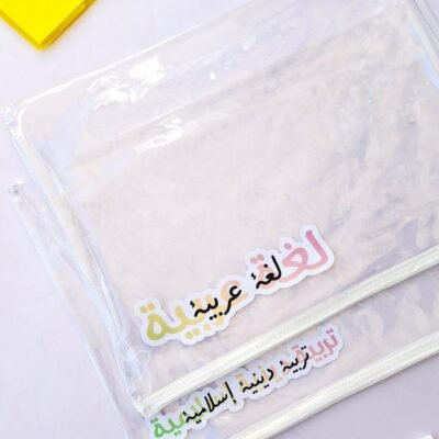 Top-down view of a clear file with colorful Arabic lettering, pens, and a yellow notebook on a soft pastel background.