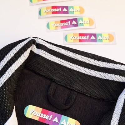 Black-and-white striped jacket with a colorful label inside; four matching labels lie above on a white background.